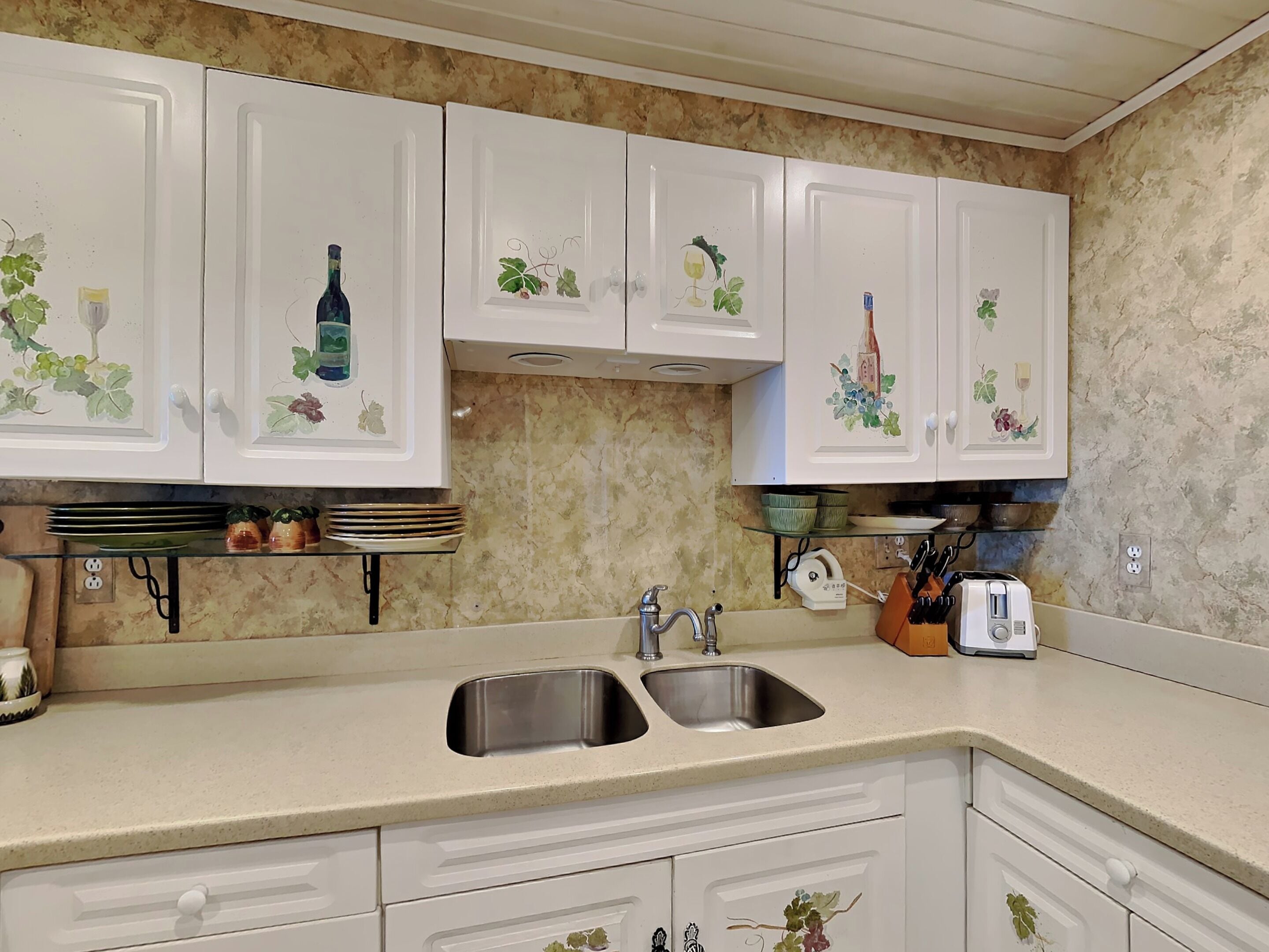 A kitchen with white cabinets, a double sink, and a toaster.