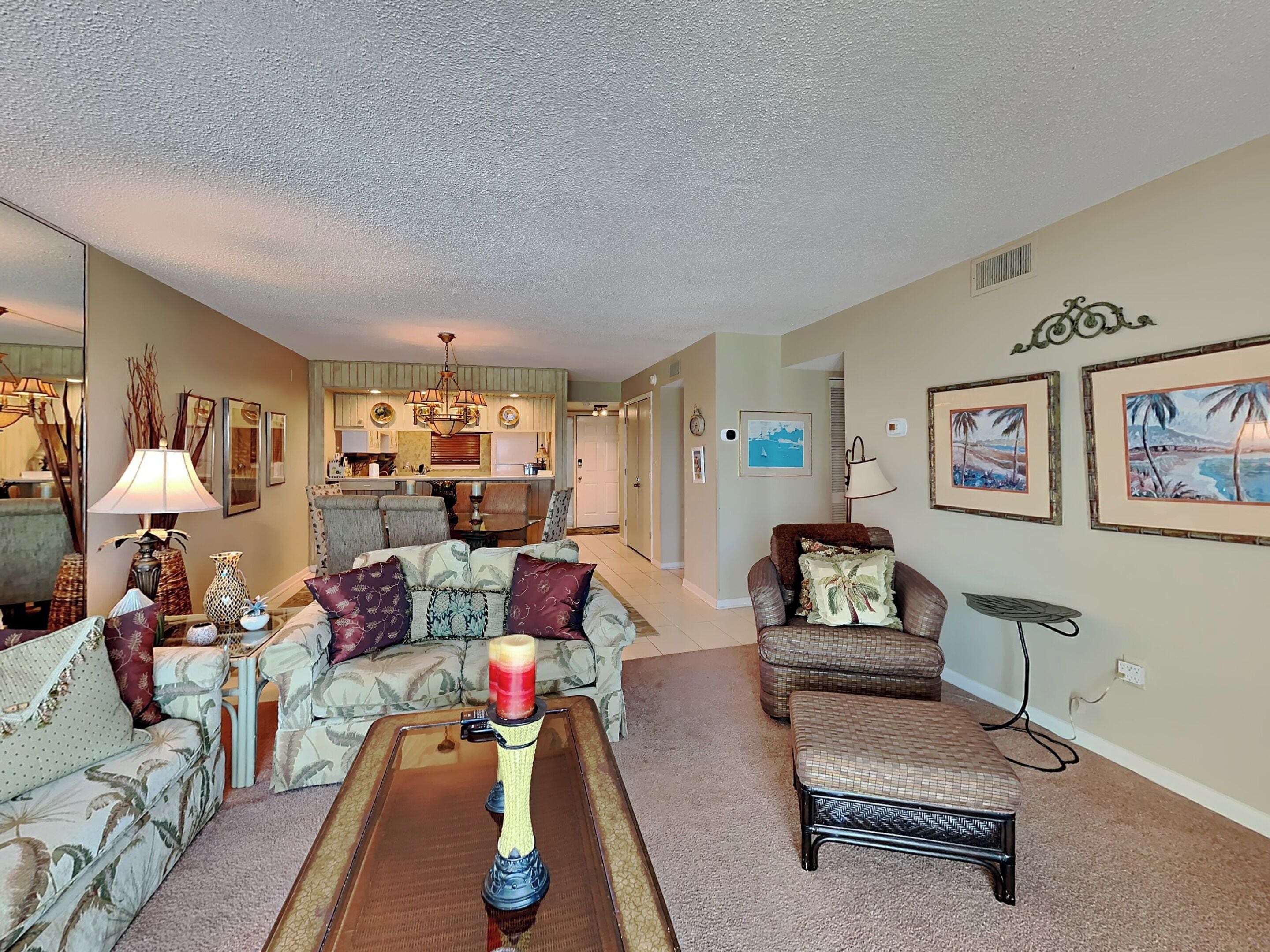 A living room with a sofa, armchairs, a coffee table, and a dining area in the background.