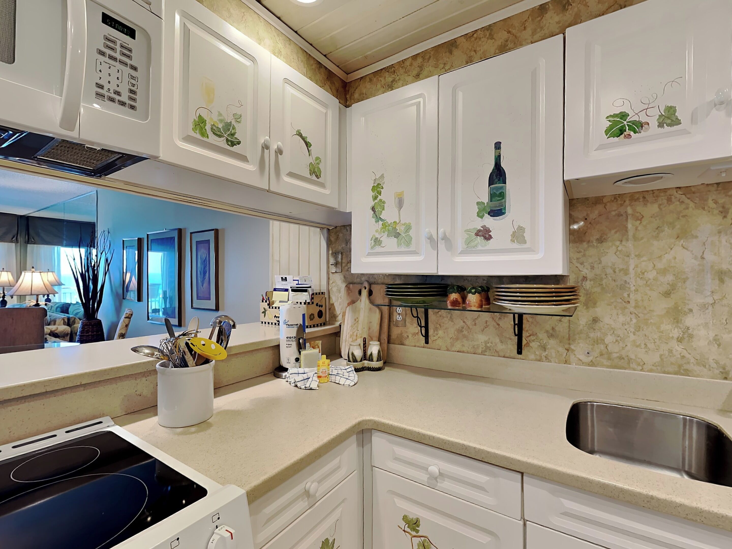 A kitchen with white cabinets, a stainless steel sink, and a microwave.