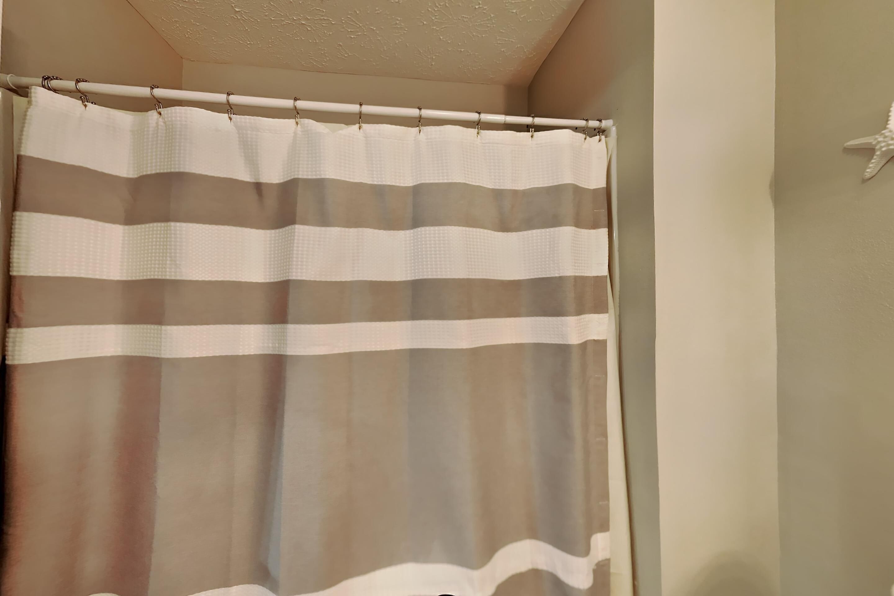 A bathroom with a striped shower curtain and a starfish decoration on the wall.