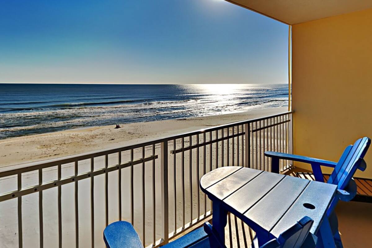 A balcony with a view of the beach and ocean.