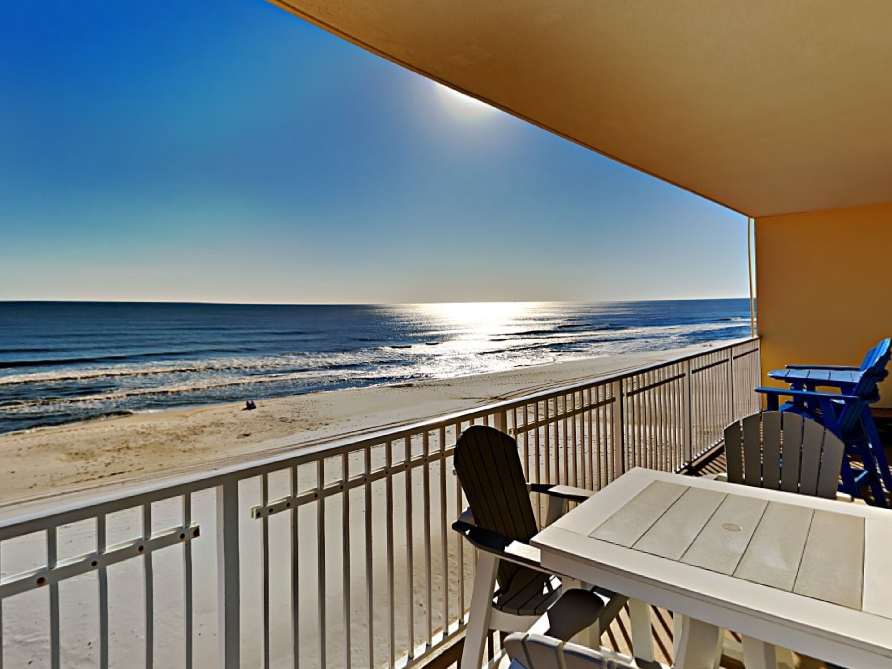 A balcony with a view of the beach and ocean.