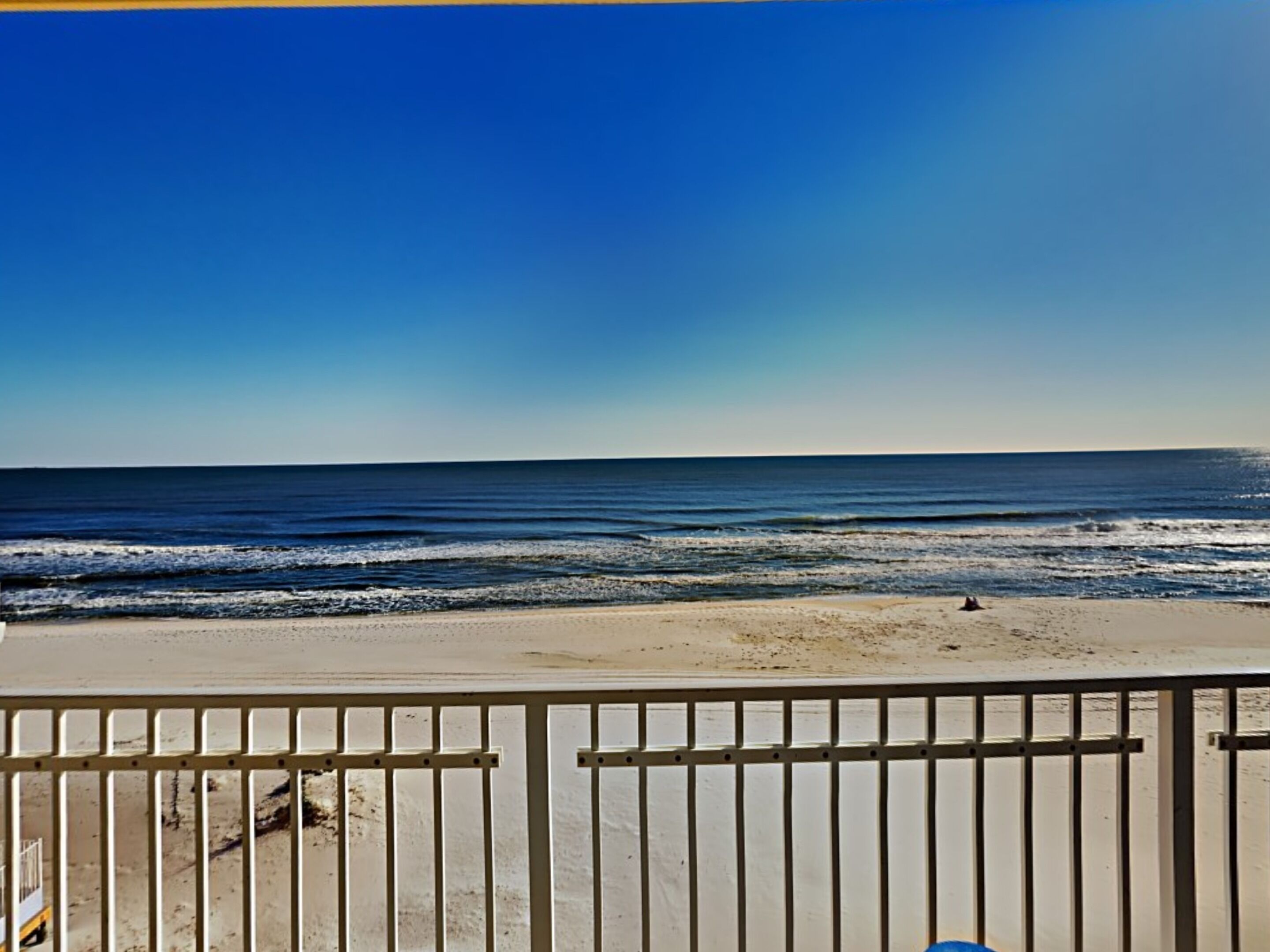 Vista de la playa con una barandilla al frente.