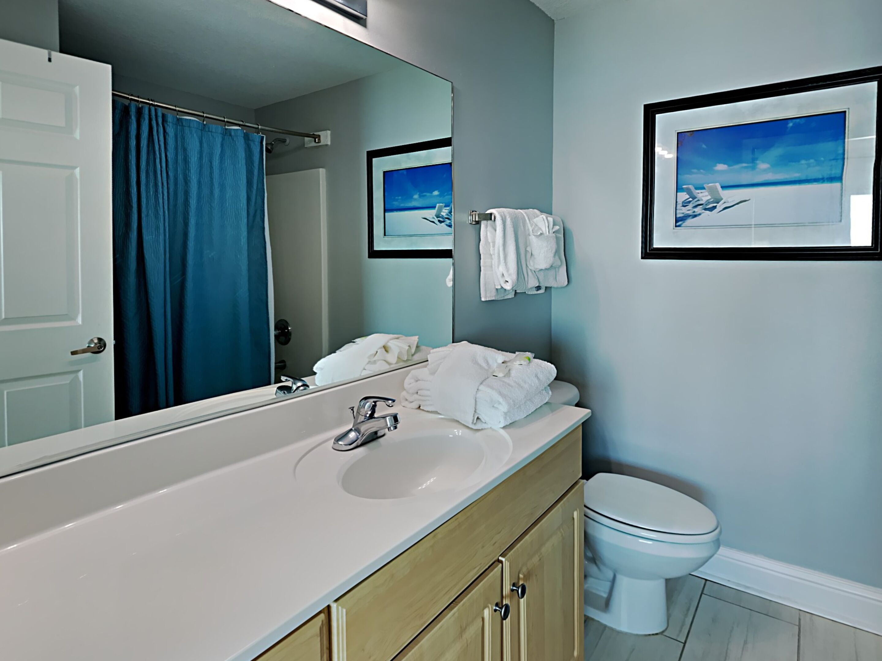 A bathroom with a white sink, a mirror, a toilet, and a shower curtain.