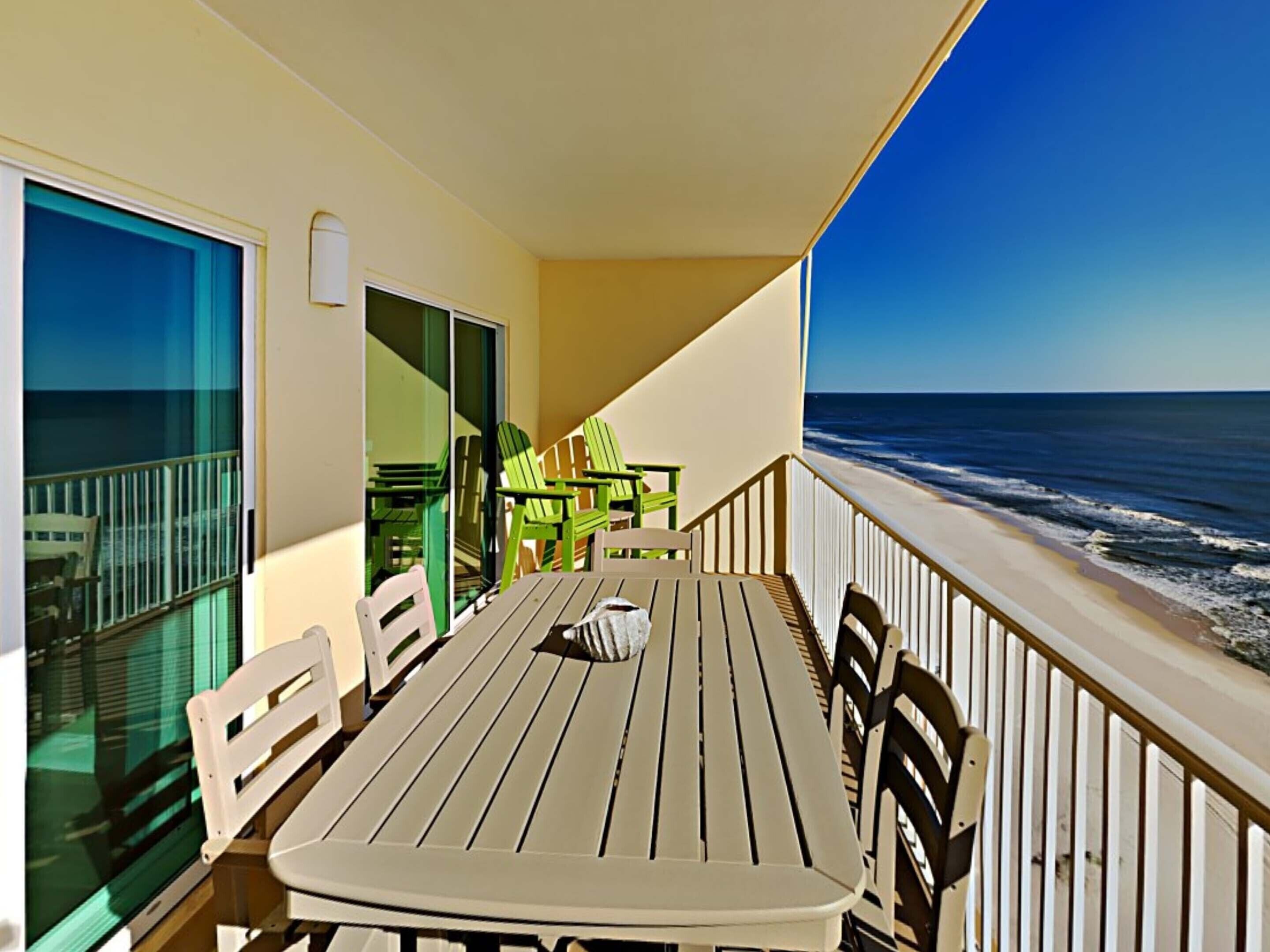 A balcony with a table and chairs, overlooking the ocean.