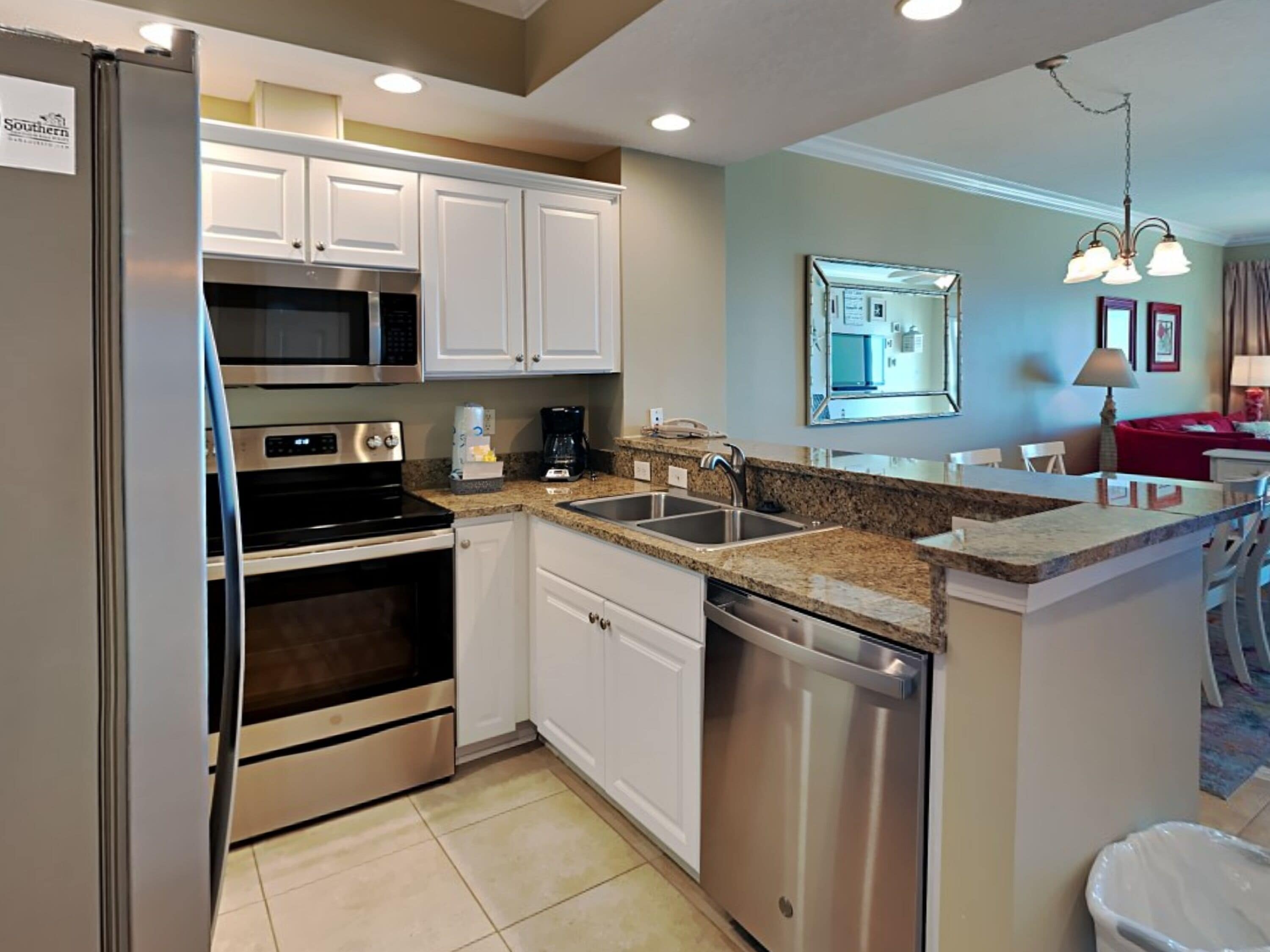 A modern kitchen with stainless steel appliances, white cabinetry, and a granite countertop.