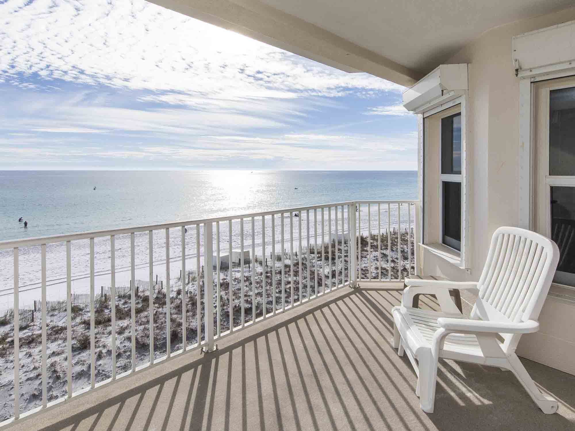 A balcony with a view of the beach and ocean.