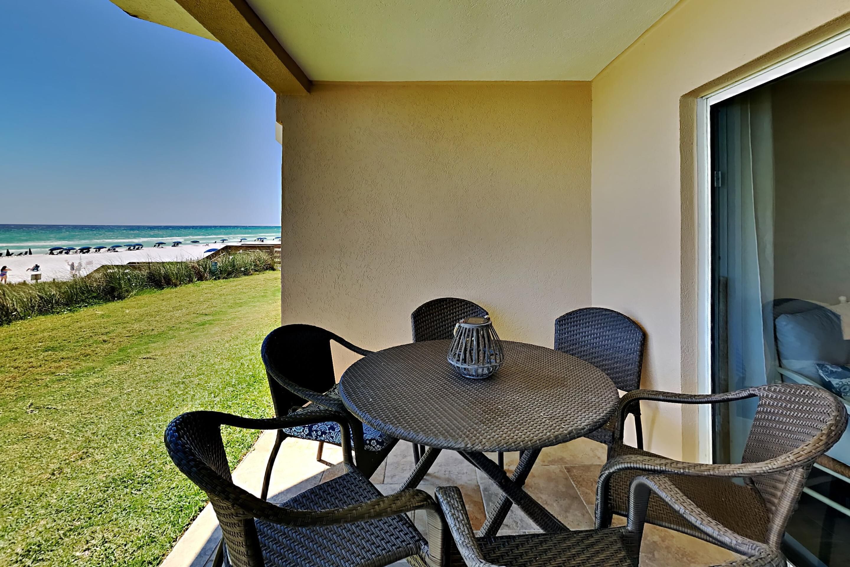 A balcony with wicker furniture and a view of the beach.
