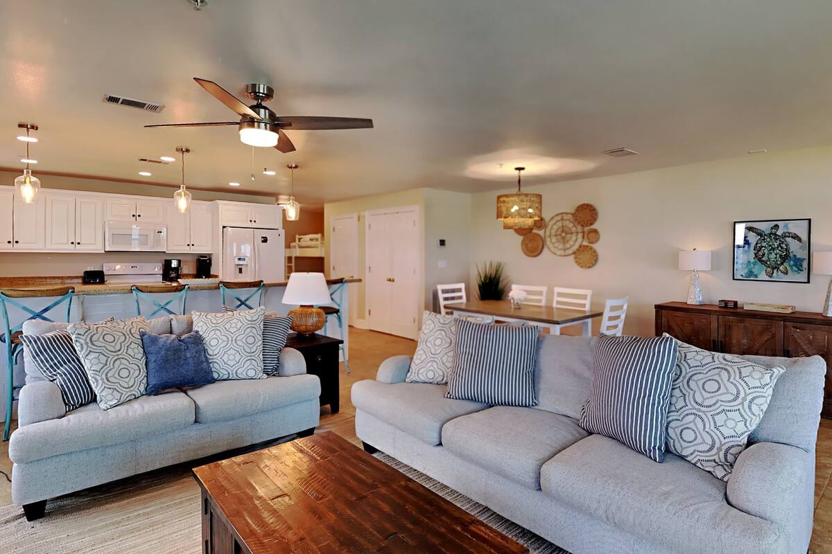 A modern living room with two sofas, a coffee table, and a dining area with a table and chairs.