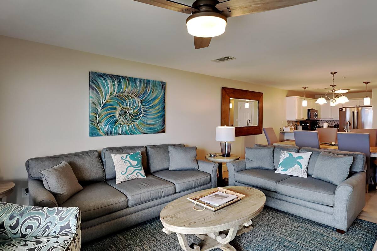 A modern living room with a grey sofa, a coffee table, and a painting on the wall.
