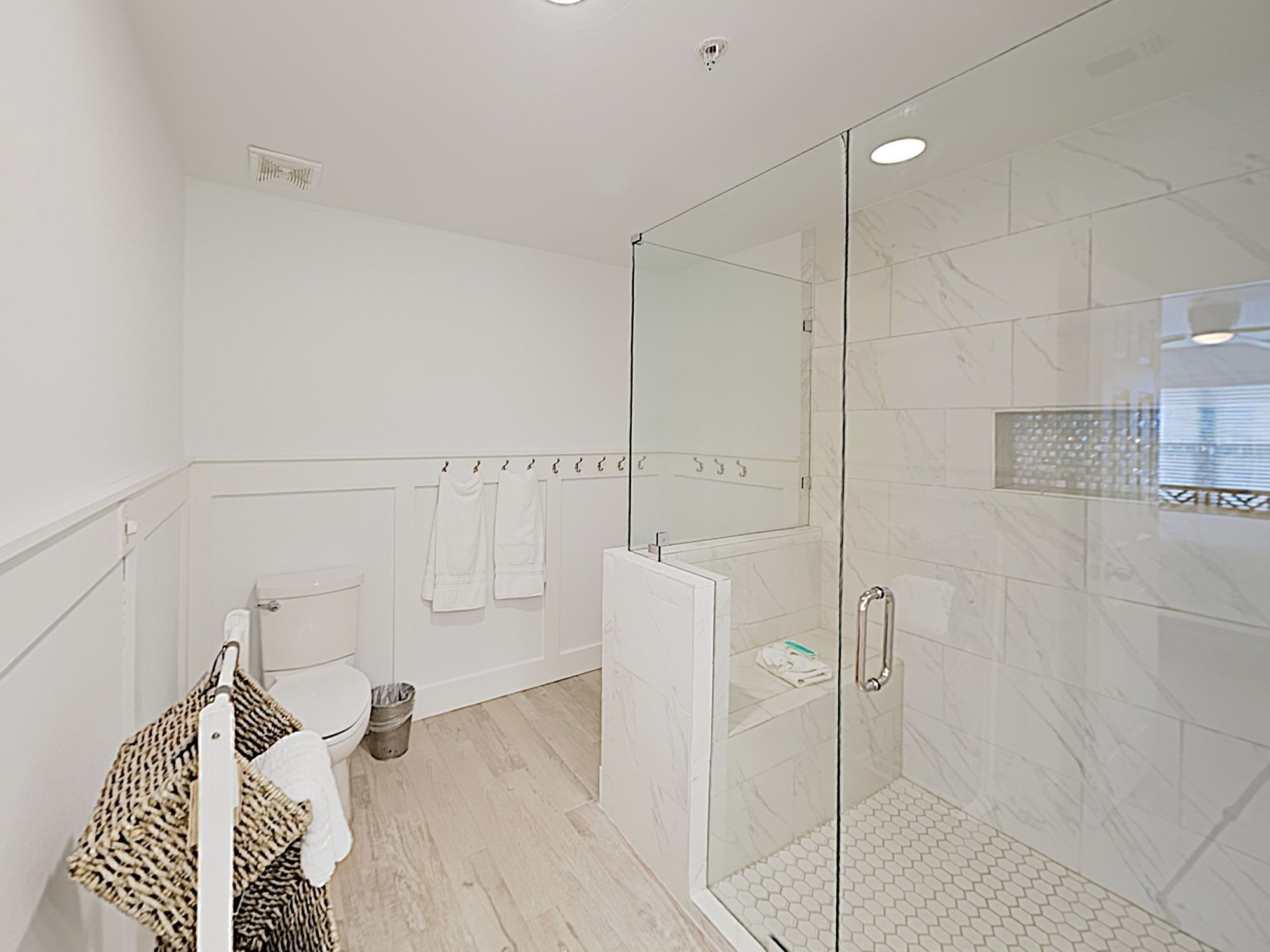 Une salle de bain moderne avec une douche à parois de verre, des toilettes et un porte-serviettes.