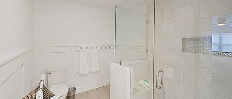 Une salle de bain moderne avec une douche à parois de verre, des toilettes et un porte-serviettes.