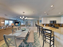 A modern living room with a dining area, kitchen, and a view of the ocean.