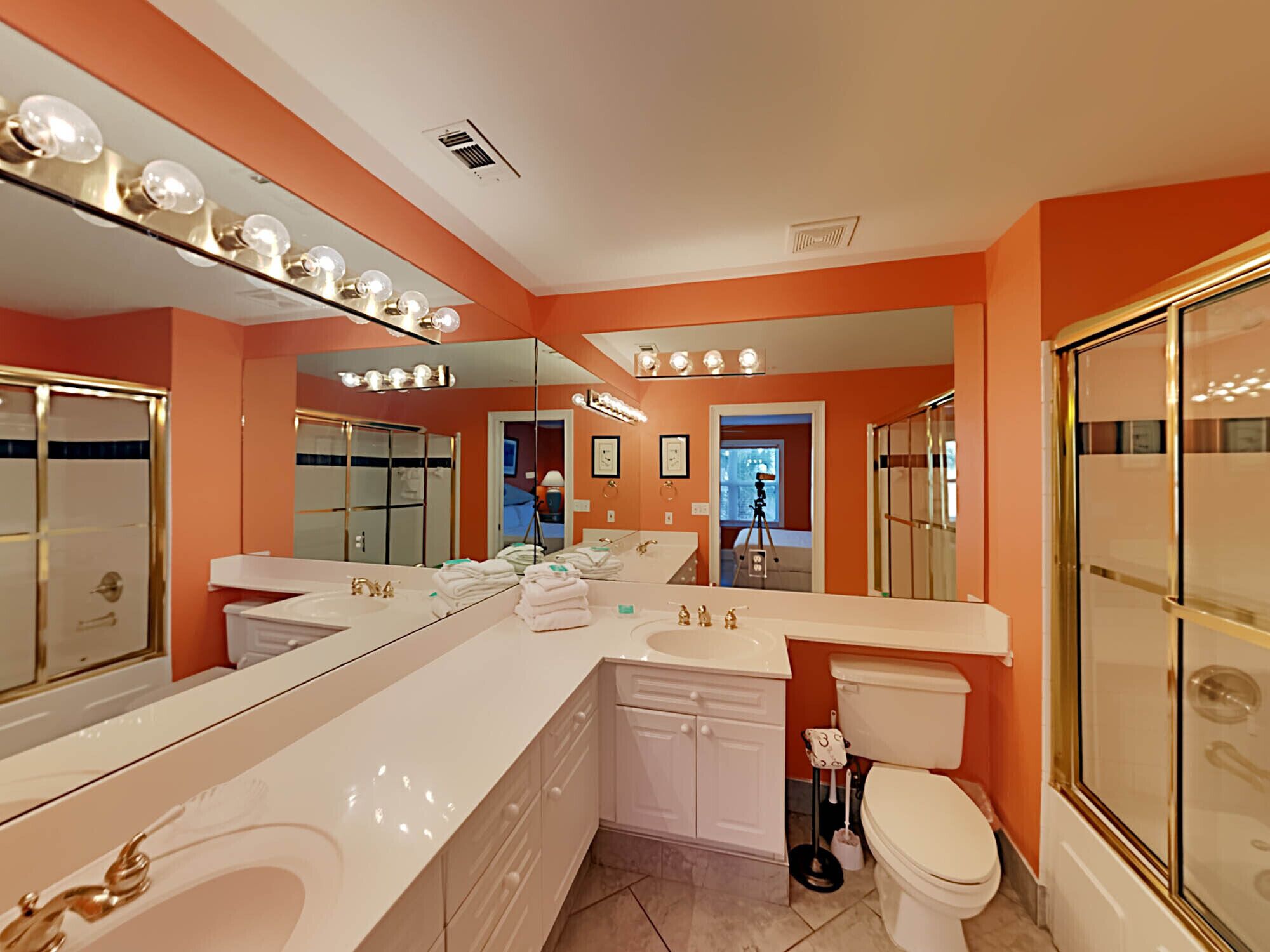 A modern bathroom with a large mirror, a bathtub, a shower, and a toilet.