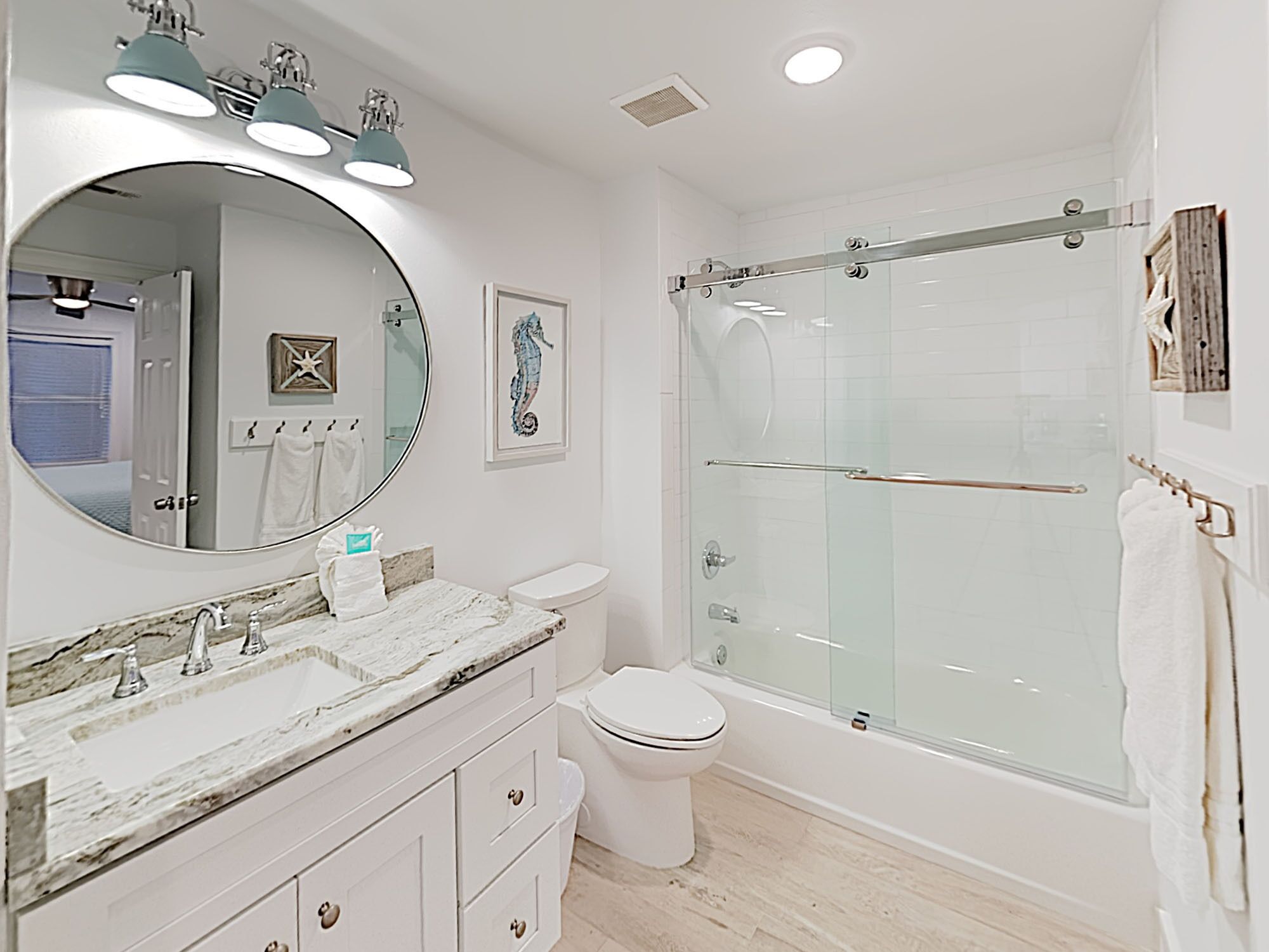 A modern bathroom with a marble vanity, a glass shower enclosure, and a large mirror.