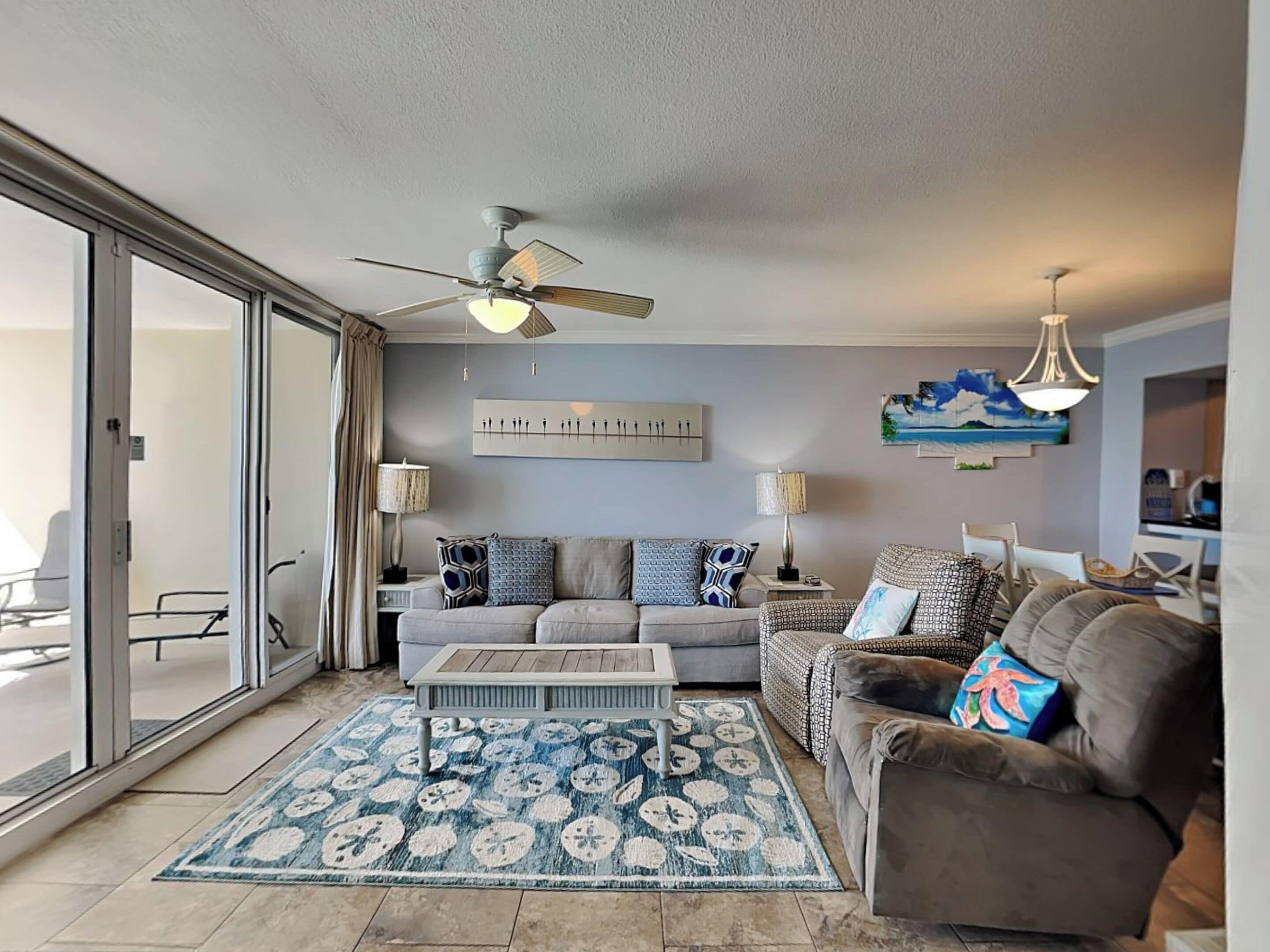 A living room with a ceiling fan, a sofa, a coffee table, and a patterned rug.