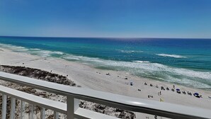 A beach with a clear sky, ocean waves, and a white railing. - Emerald Beach by Southern Vacation Rentals (Panama City Beach)
