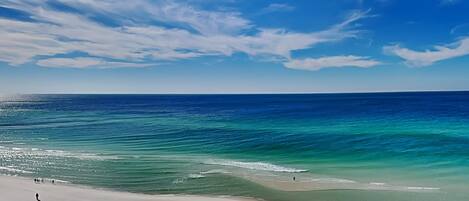A beach with clear blue water and a sandy shore.