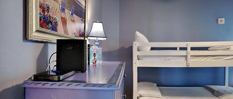 A room with a bunk bed, a desk with a computer, a lamp, and a framed painting.