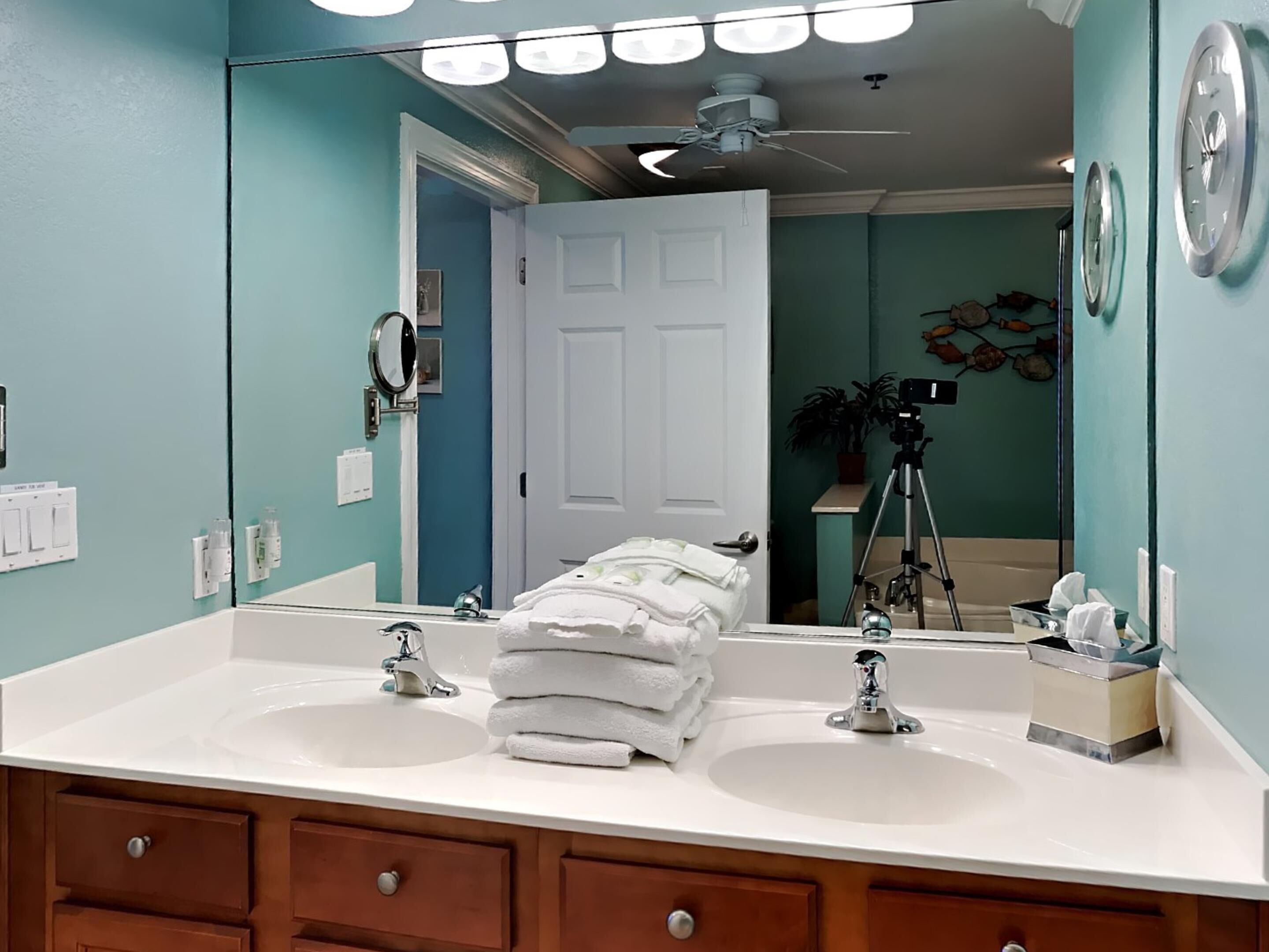 A bathroom with two sinks, a large mirror, and a ceiling fan.