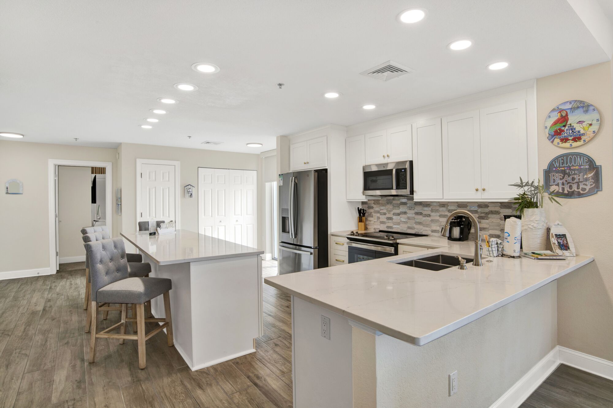 A modern kitchen with white cabinetry, stainless steel appliances, and a central island.