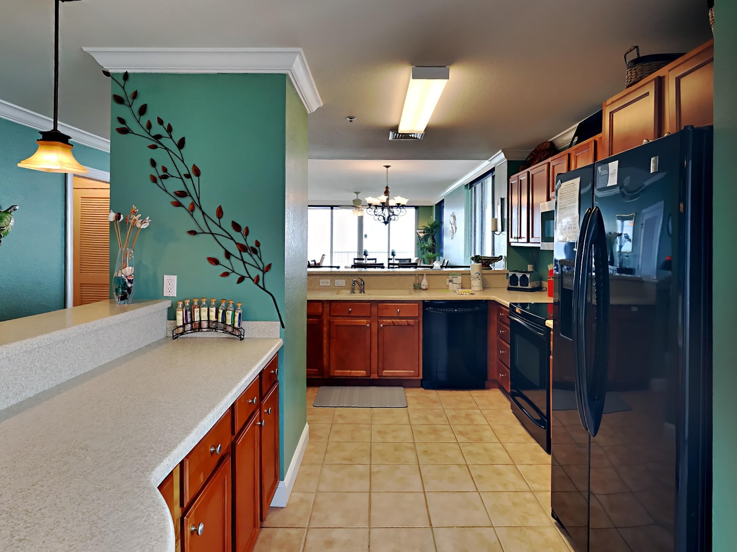 Een moderne keuken met houten kastjes, een zwarte koelkast en een muur in een turquoise kleur.