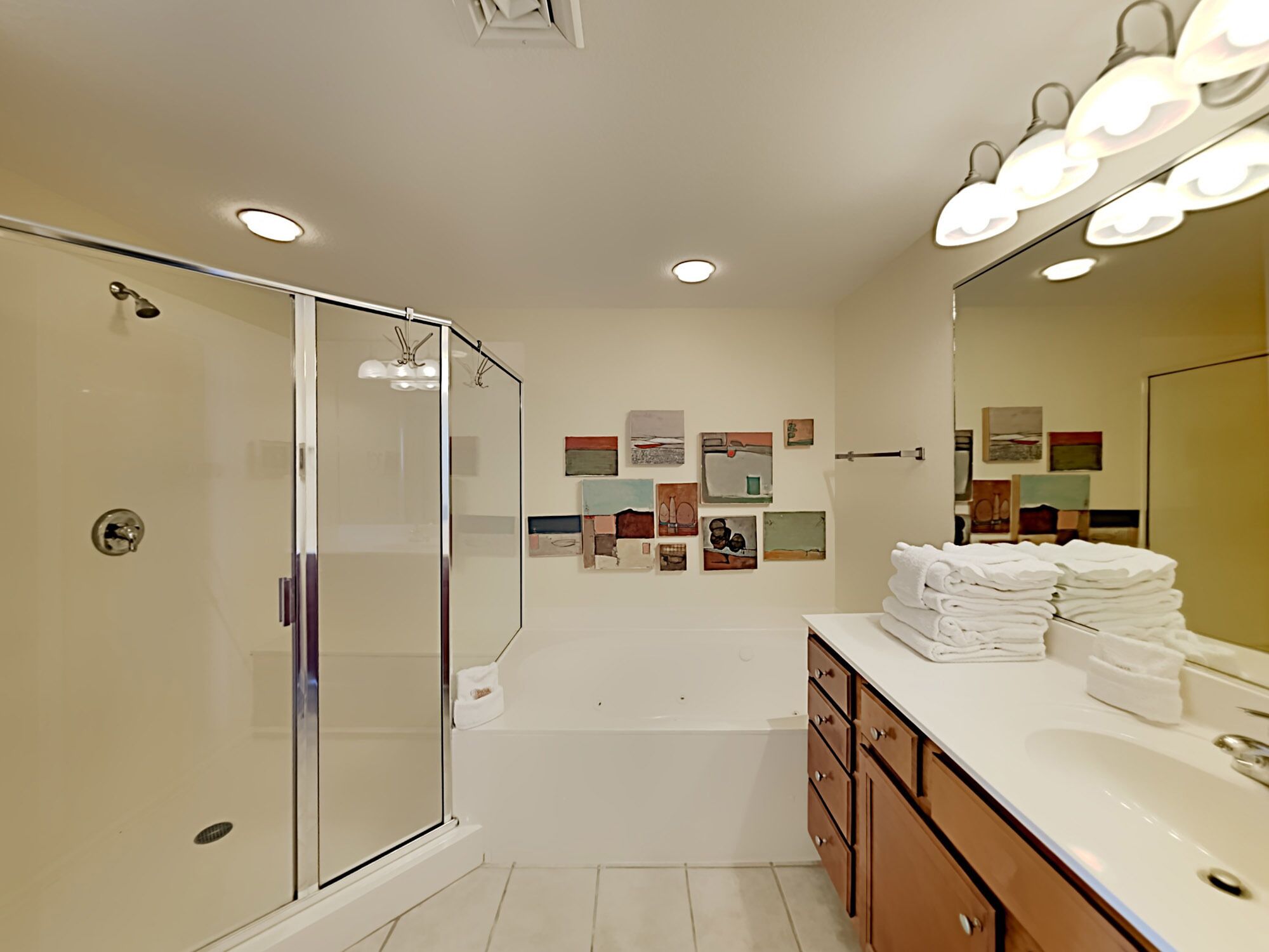 Un baño moderno con cabina de ducha de vidrio, una bañera y un tocador con una pila de toallas.