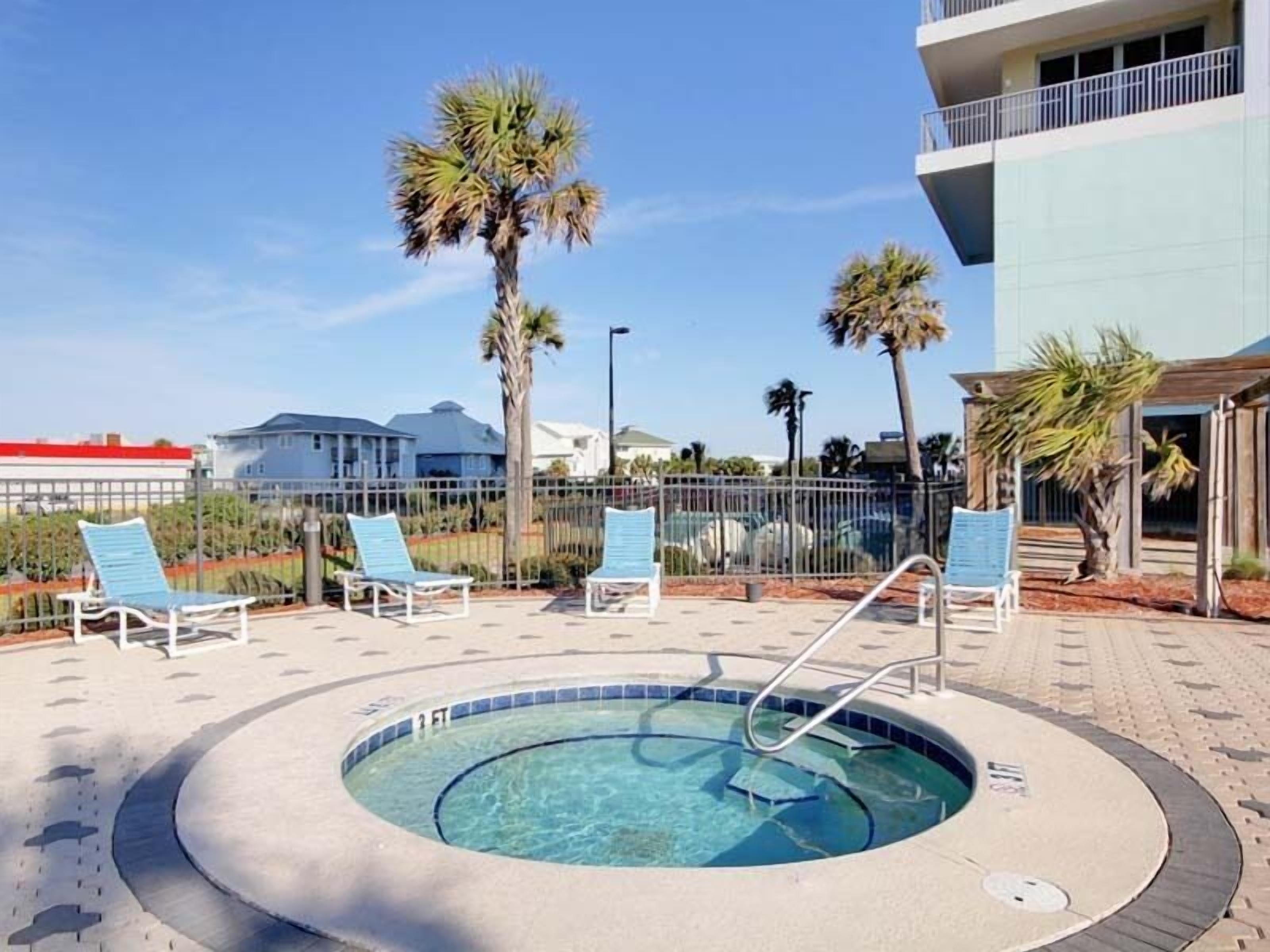 A pool area with lounge chairs and a hot tub.