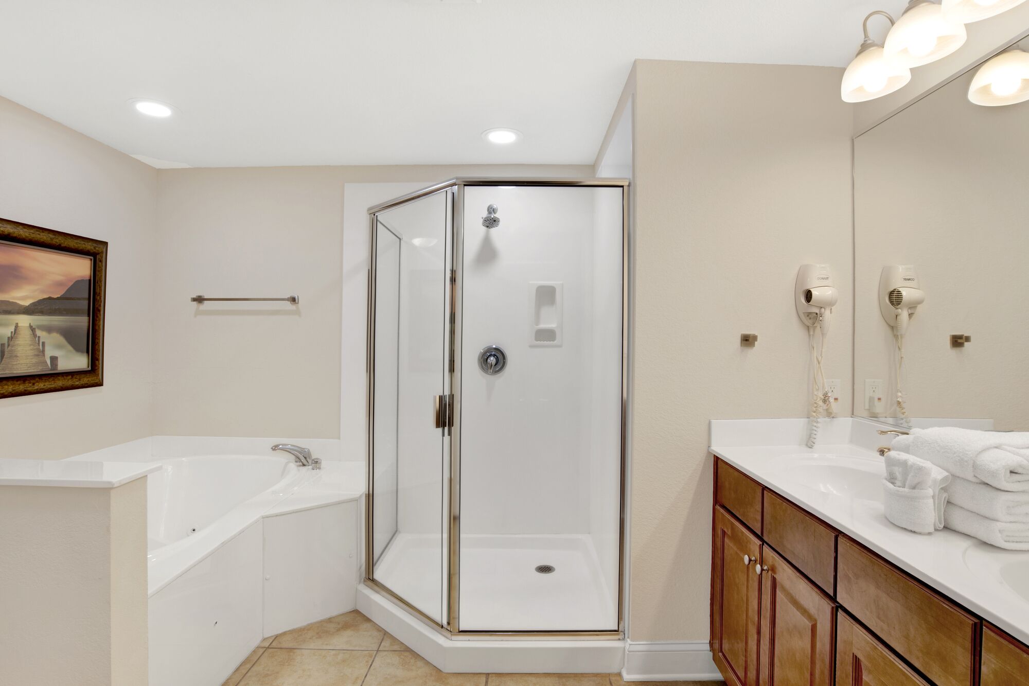 A modern bathroom with a glass-enclosed shower, a white bathtub, and a vanity with a mirror and towel rack.