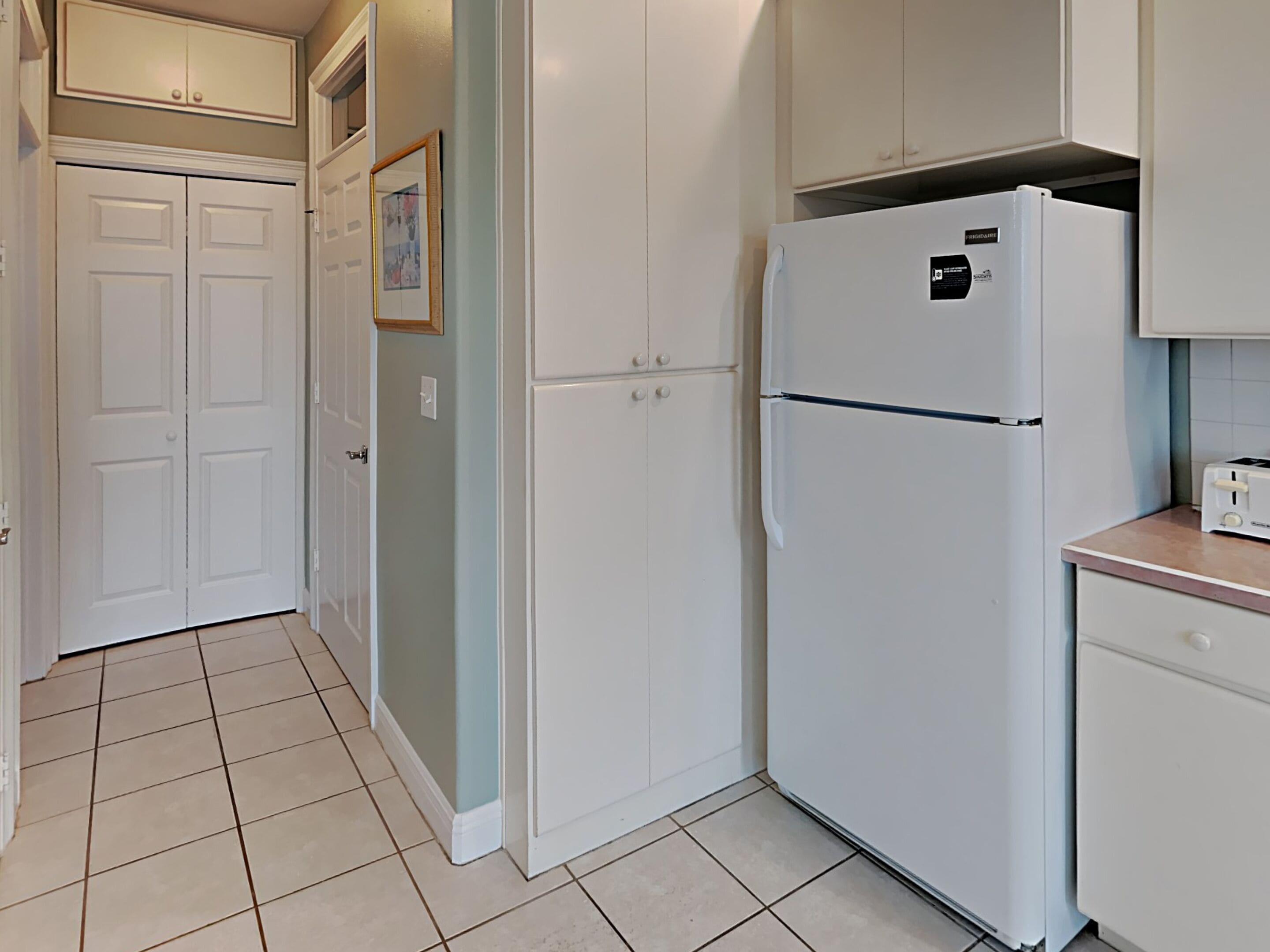 A kitchen with white cabinets, a white refrigerator, and a toaster on the countertop.