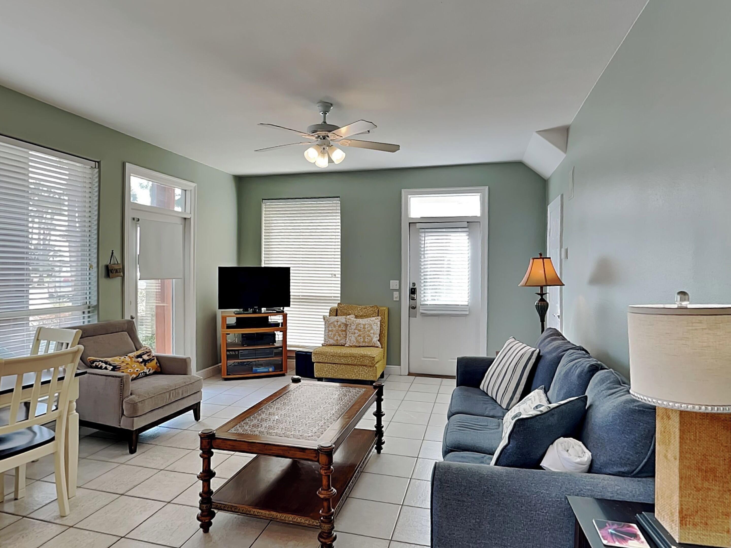 A living room with a television, sofa, coffee table, and a ceiling fan.