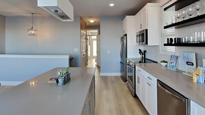 A modern kitchen with a central island, stainless steel appliances, and a built-in microwave shelf. - Destiny Beach Villas by Southern Vacation Rentals (Destin)
