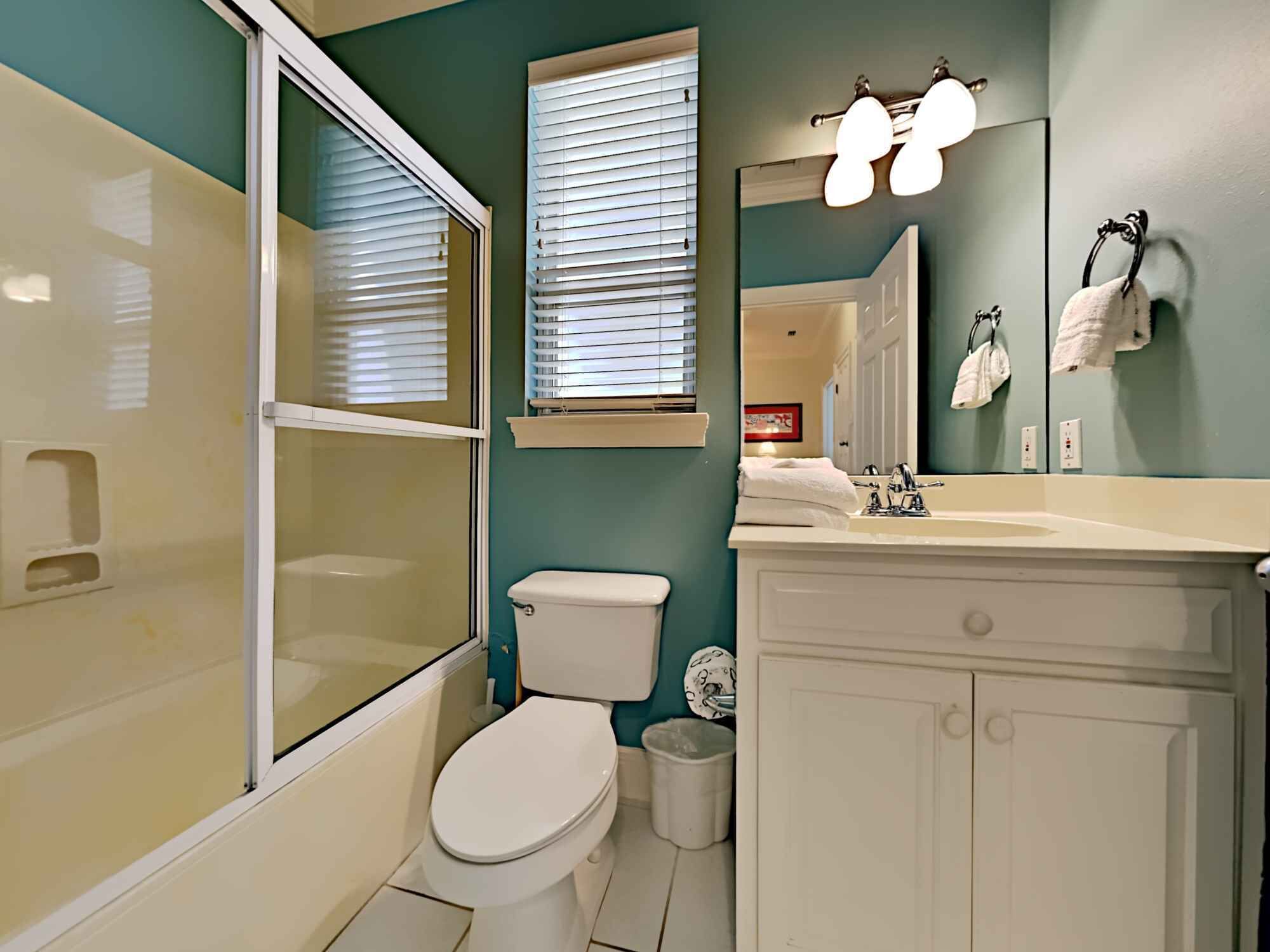 A bathroom with a toilet, sink, and mirror.