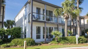 A two-story building with a balcony on the upper floor, surrounded by palm trees and greenery. - Destiny Beach Villas by Southern Vacation Rentals (Destin)