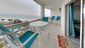 A balcony with a view of the ocean, white furniture, and a welcome mat. - El Matador by Southern Vacation Rentals (Fort Walton Beach)