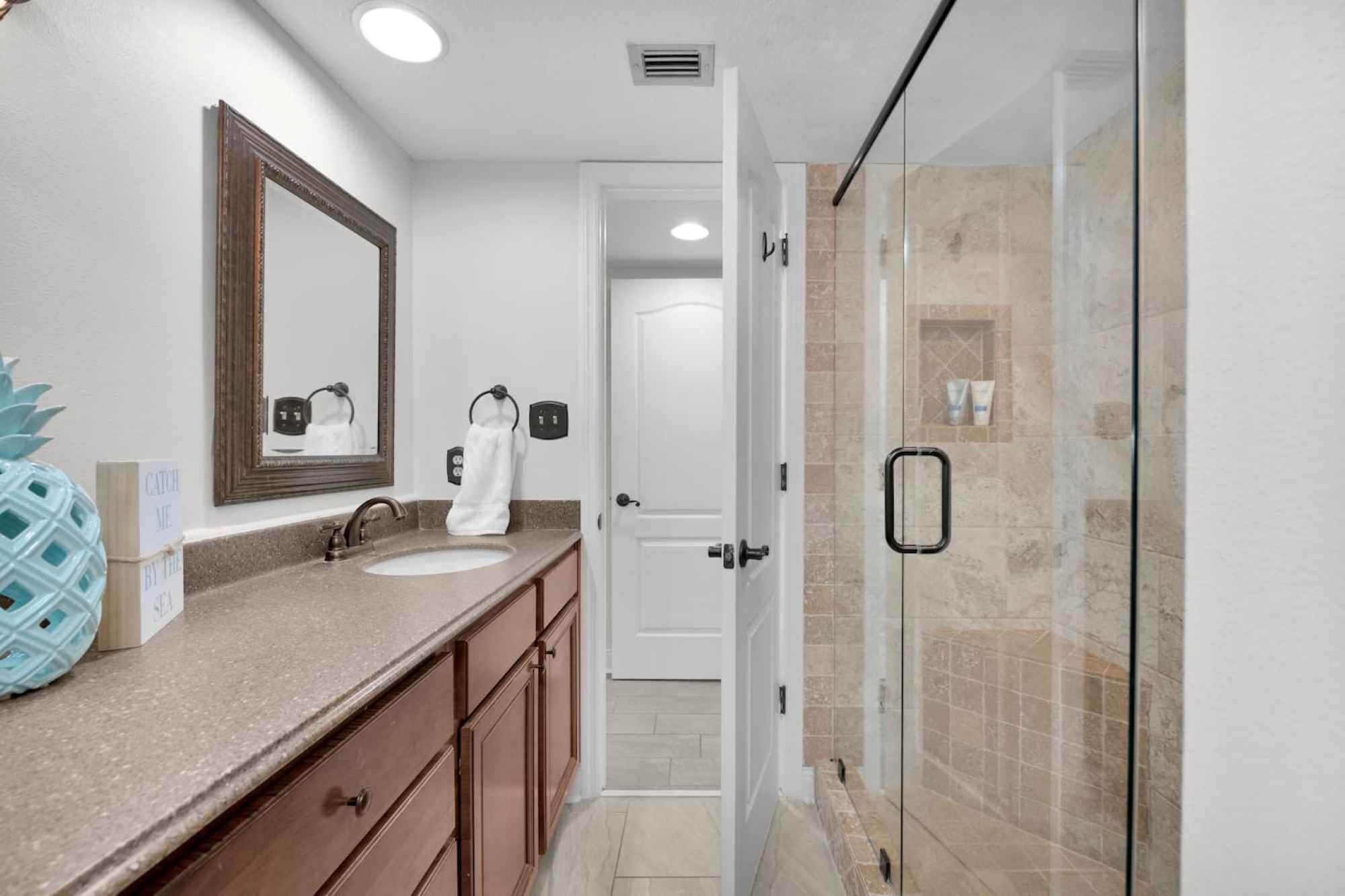 A bathroom with a sink, mirror, and towel rack. There is a door leading to another room.