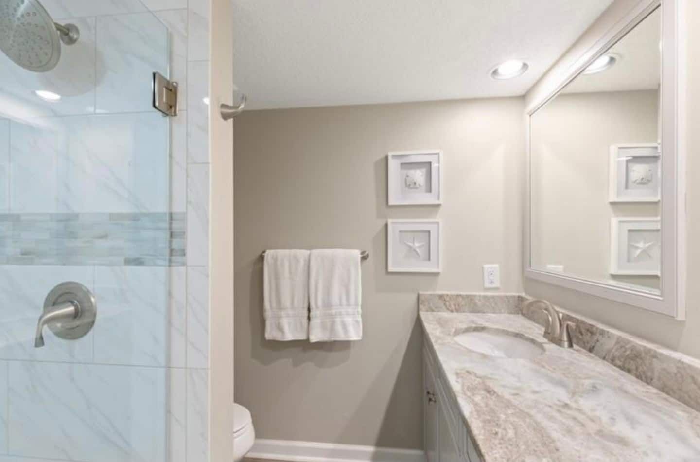 A bathroom with a shower, toilet, and vanity with a mirror.
