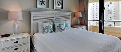 Habitación de hotel ordenada con una cama grande, dos mesitas de noche, una lámpara y cuadros en la pared.