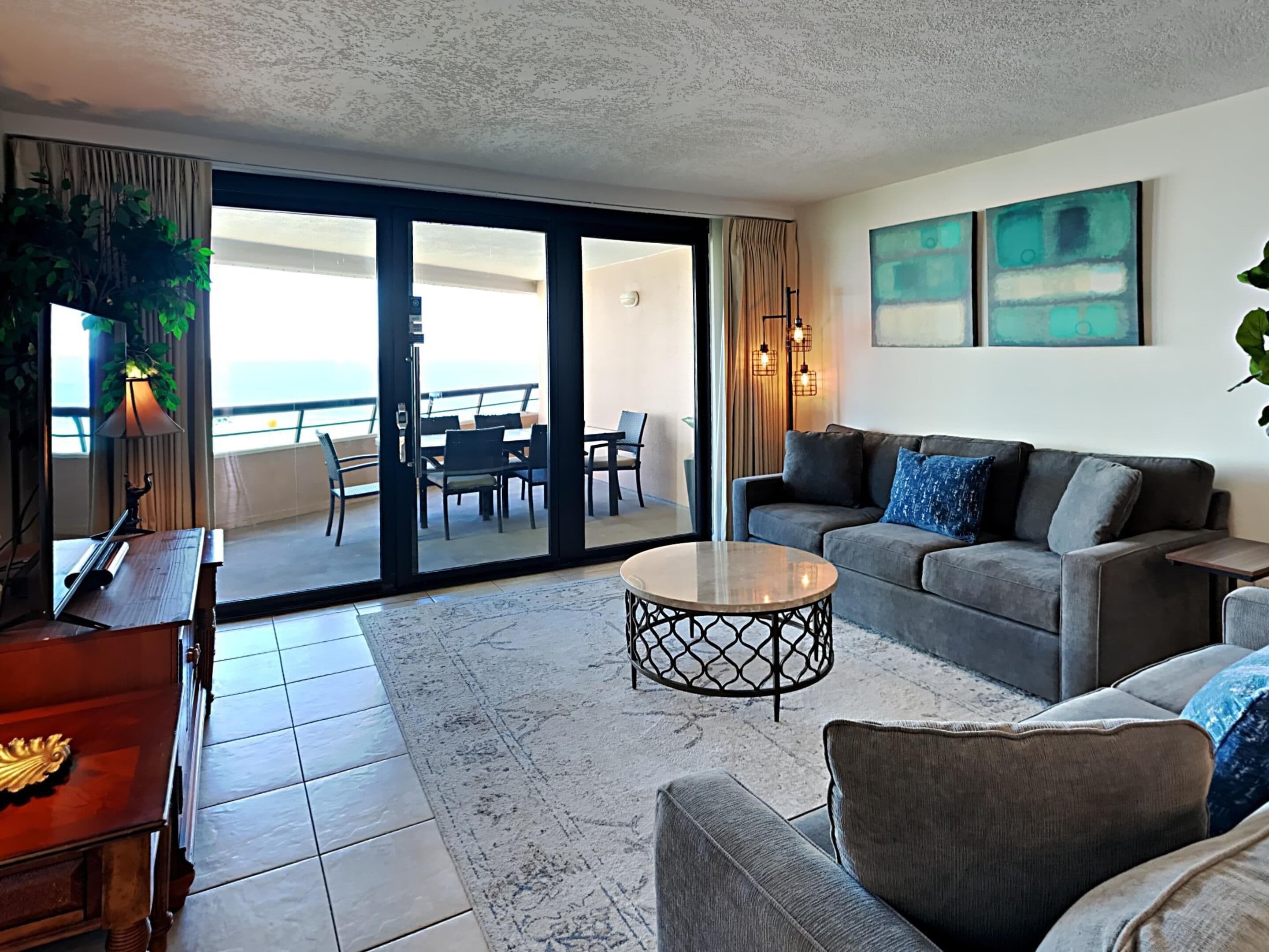 A living room with a sofa, coffee table, and a dining area with chairs and a table.