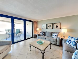 A living room with a sofa, armchairs, a coffee table, and a balcony with chairs. - Edgewater by Southern Vacation Rentals (Miramar Beach)