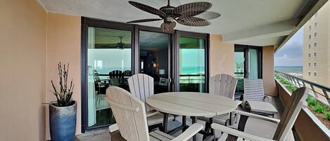 Een balkon met een tafel en stoelen, een plafondventilator en uitzicht op de oceaan.