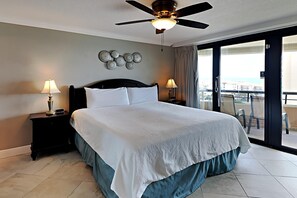 A hotel room with a large bed, two bedside lamps, a ceiling fan, and a balcony with a view. - Edgewater by Southern Vacation Rentals (Miramar Beach)