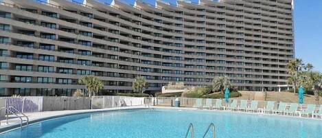 Un hotel grande con piscina y vista a un edificio alto al fondo.