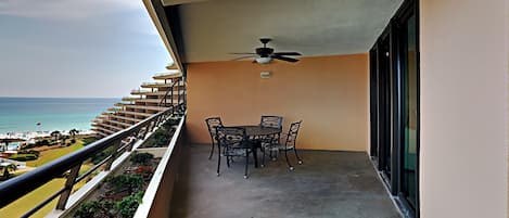 Uma varanda com mesa e cadeiras, um ventilador de teto e vista para o oceano.