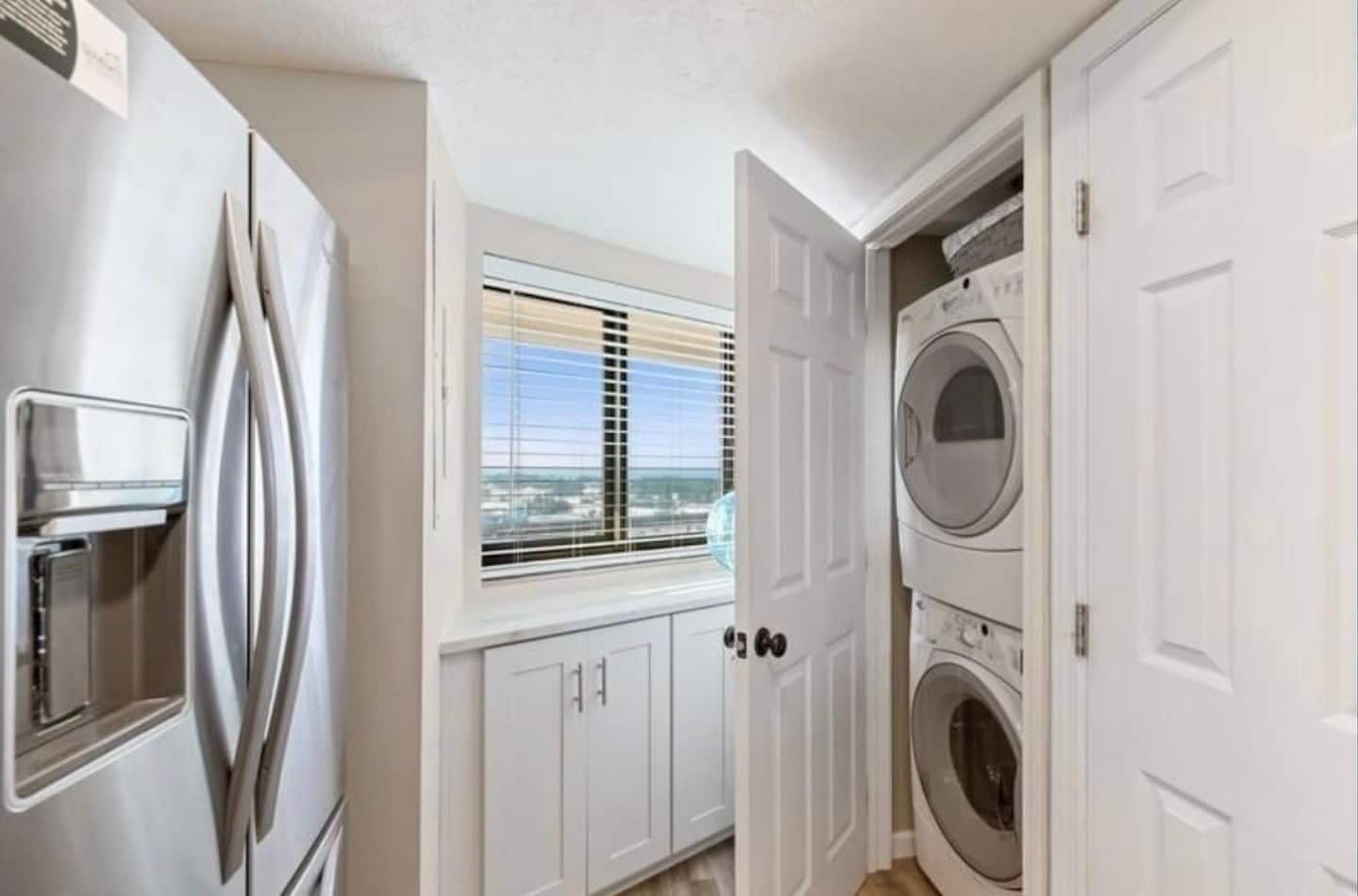 Un lavadero equipado con lavadora y secadora, un refrigerador y una ventana con persianas.