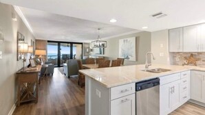 A spacious kitchen with a large island, modern appliances, and a view to the outside. - Edgewater by Southern Vacation Rentals (Miramar Beach)