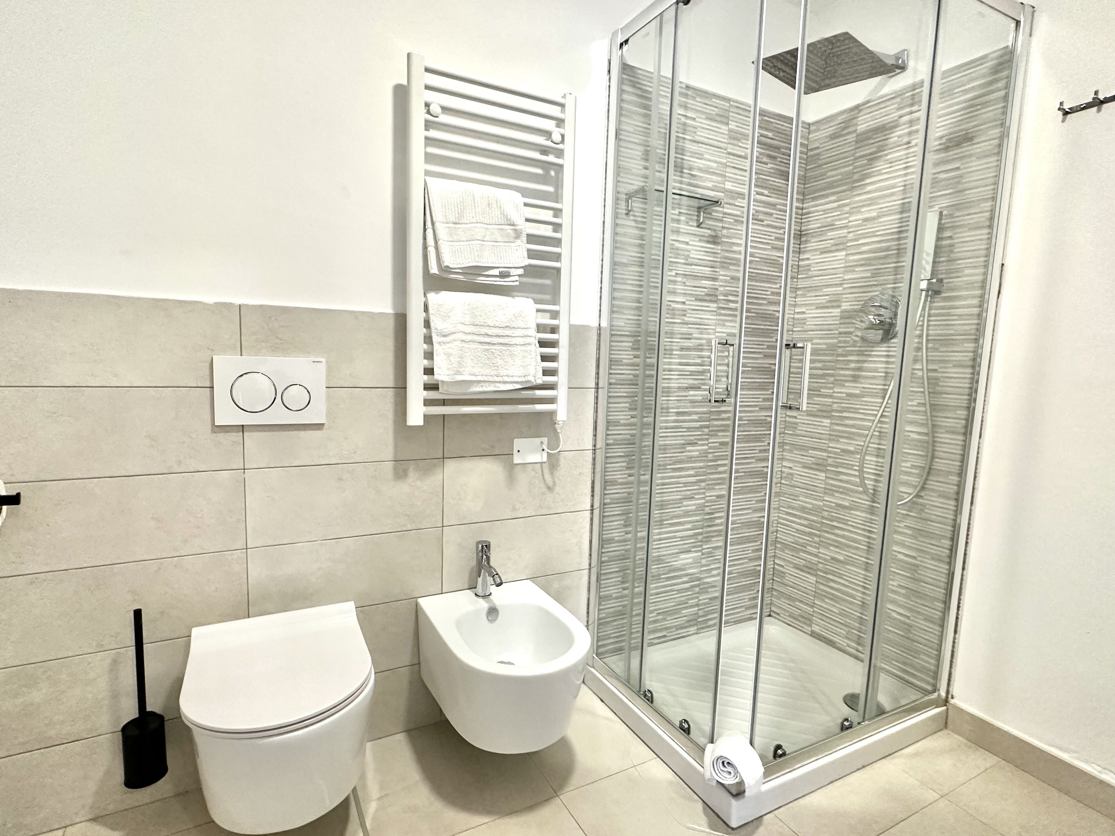 A modern bathroom with a toilet, bidet, and glass-enclosed shower.