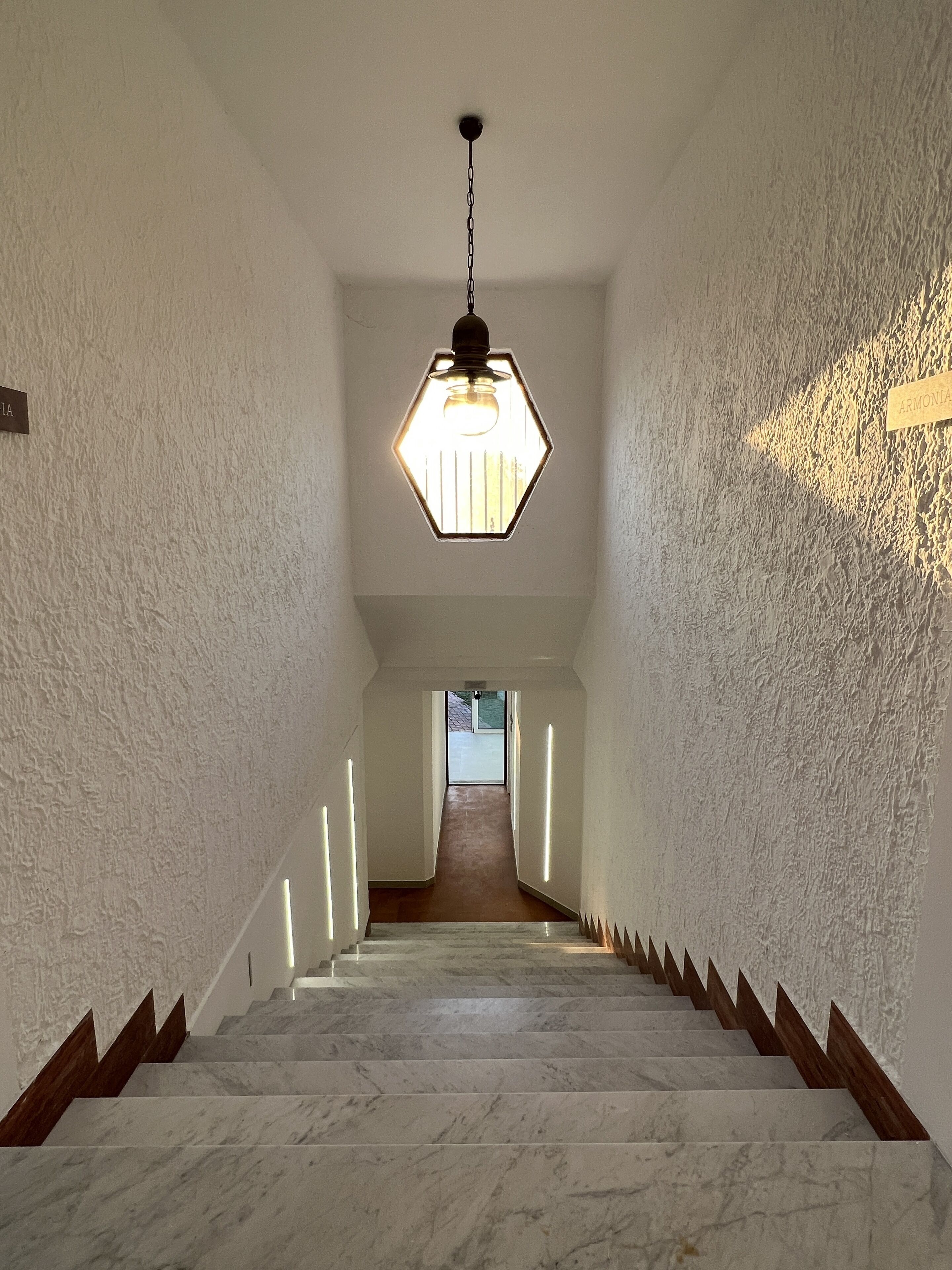 A staircase with marble steps and wooden handrails, leading to a door at the top.