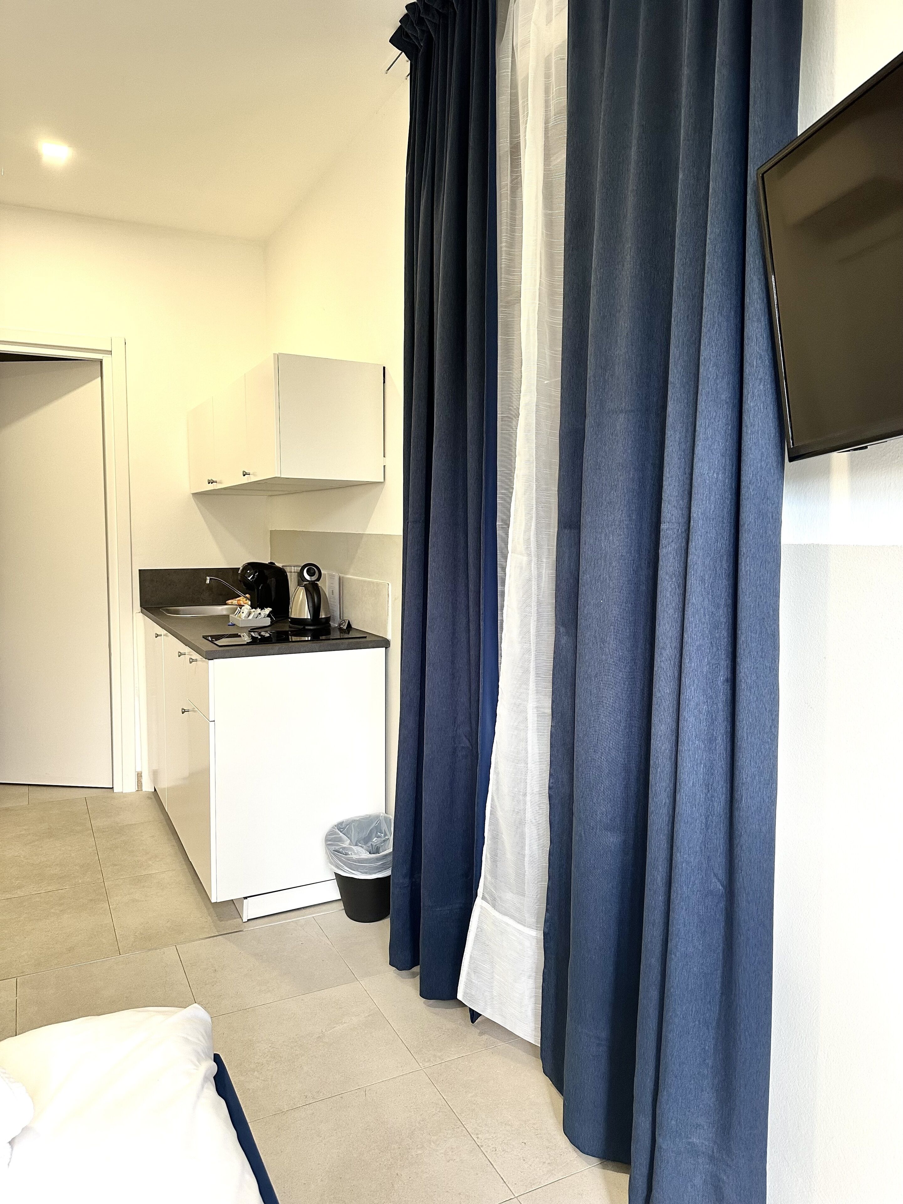 Una stanza moderna e accogliente con angolo cottura, un letto e una TV a parete.