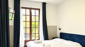 A bedroom with a bed, a window with curtains, a television, and a bedside table. - Abitatt (Fosdinovo)